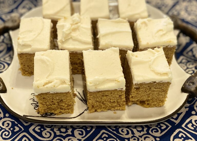 Spiced Pumpkin Bars with Browned Butter Frosting, cut into squares, displayed on a white tray atop a blue and white decorative linen